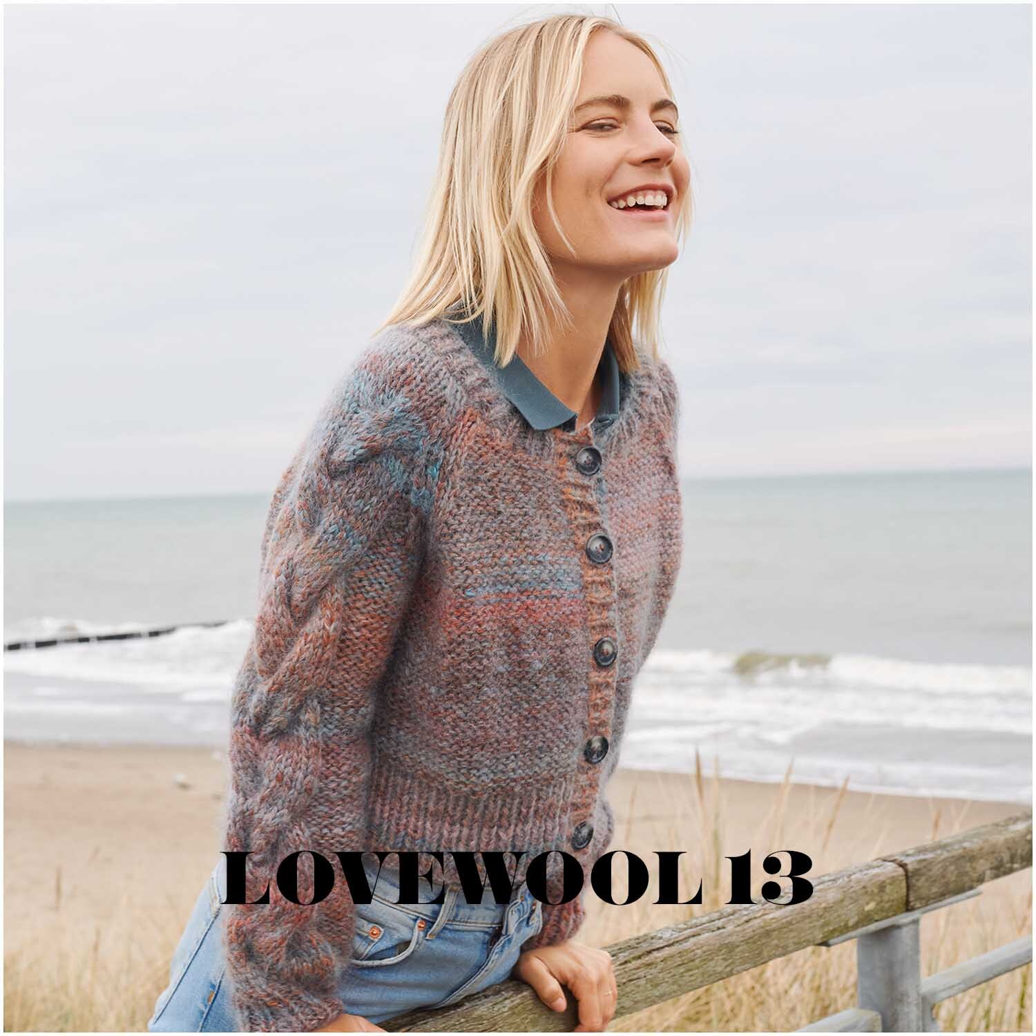 Creative Mohair Melange: Frau am Strand in gestrickter Jacke, lächelnd, mit Meer im Hintergrund.