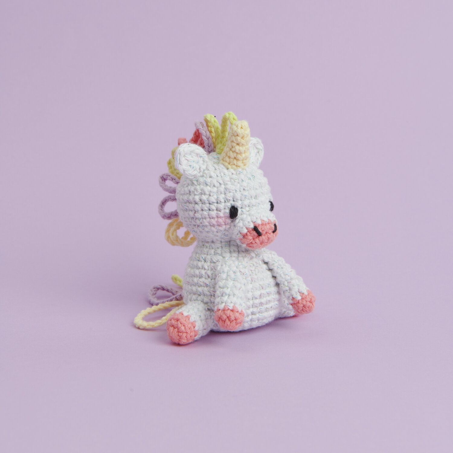 Ricorumi Mini Easy Häkelset - Einhorn: Weißes Einhorn mit bunter Mähne auf lila Hintergrund.