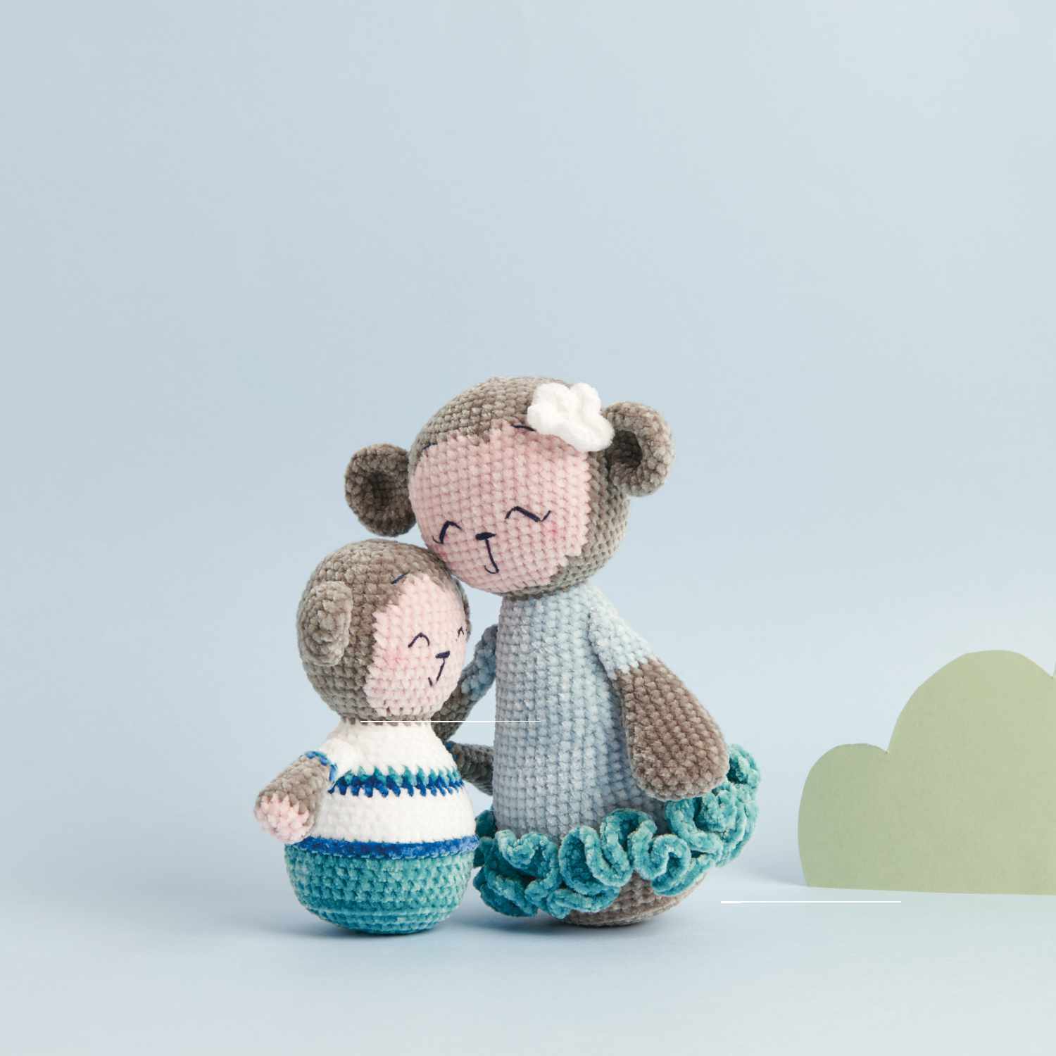 Häkelset Affenmama & Max aus Ricorumi Mini Me: Zwei gehäkelte Affen in Blau- und Brauntönen vor einem hellblauen Hintergrund.