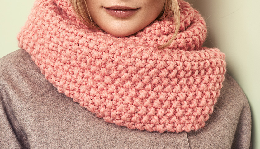 Strickanleitung Perlmuster Loop und Rippenmuster Mütze: Frau trägt rosa gestrickten Loop.