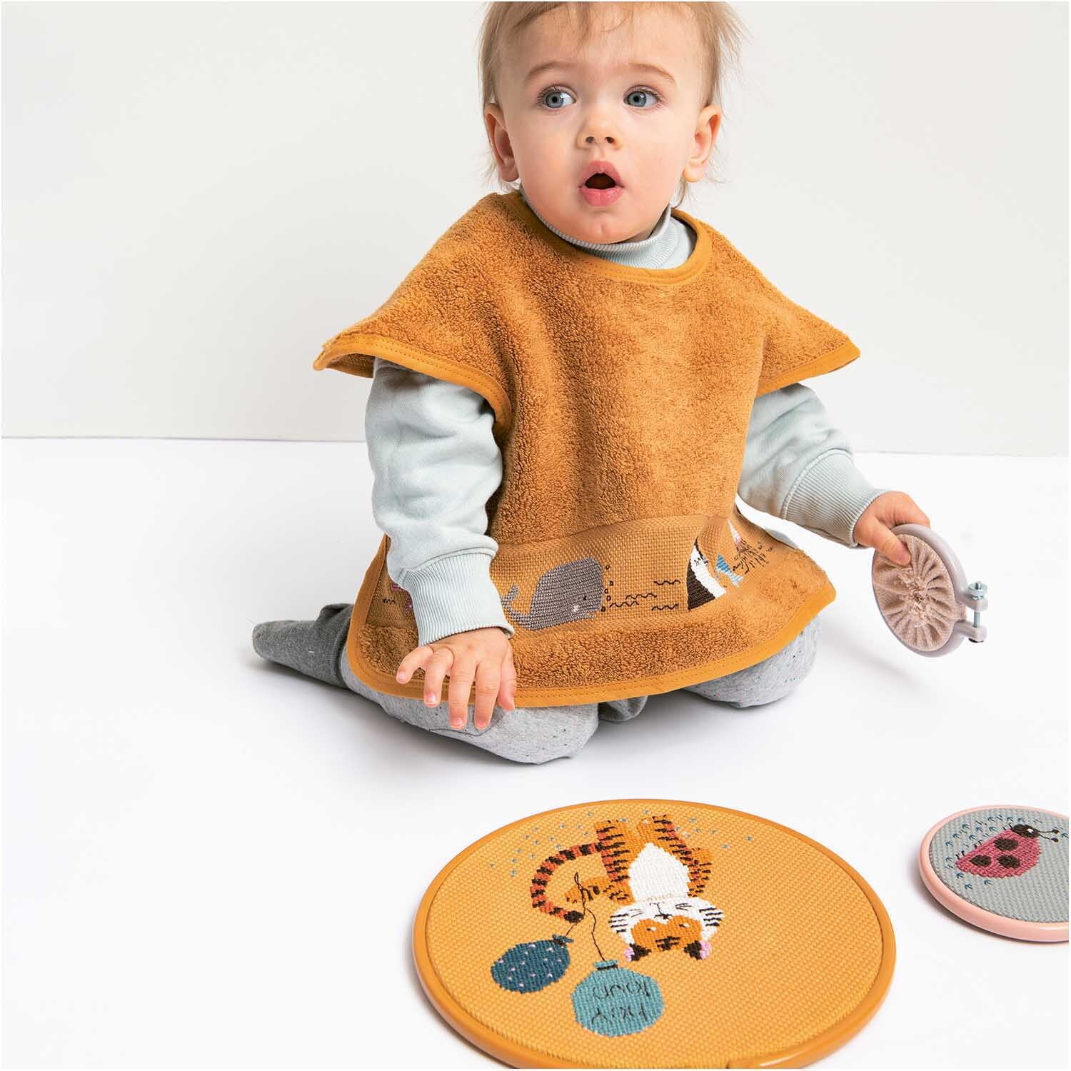 Stickring aus Kunststoff lavendel 7,6cm: Ein Kleinkind spielt mit einem Stickring und trägt ein orangefarbenes Lätzchen.