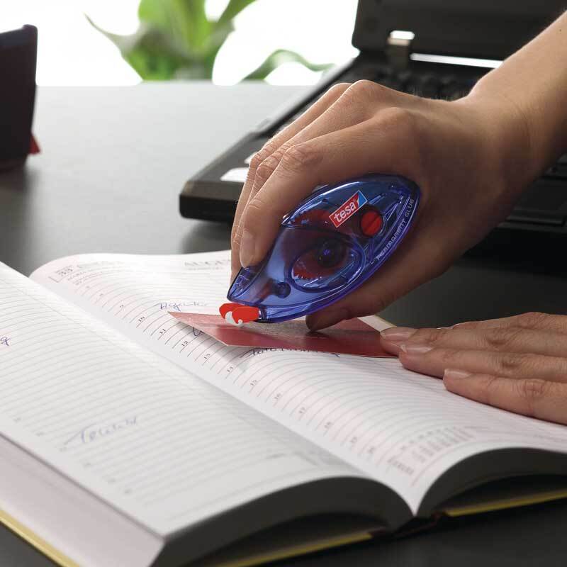 Kleberoller permanent 8,4mm 8,5m: Eine Hand nutzt einen blauen tesa Kleberoller auf einem geöffneten Notizbuch.
