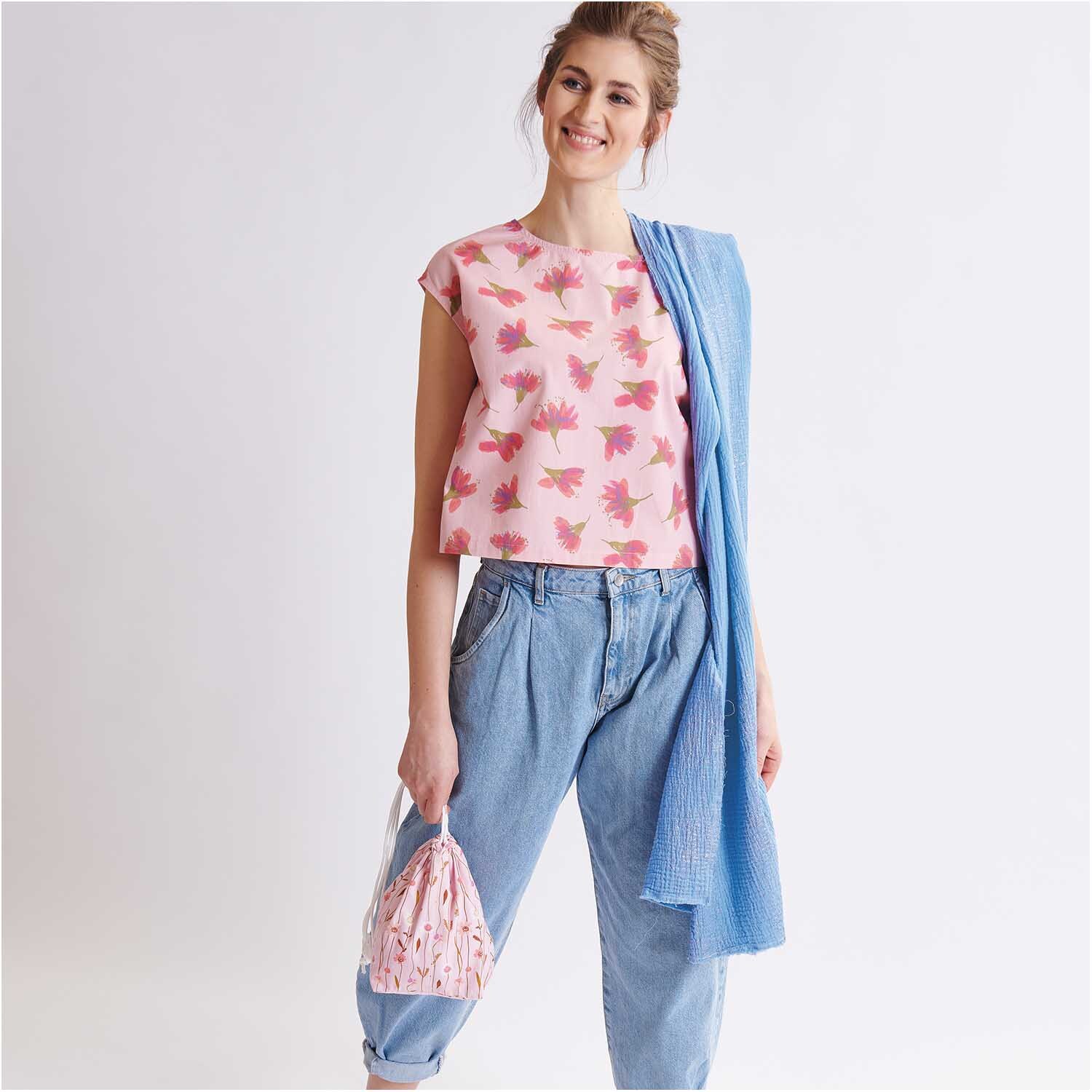 Meterware Druckstoff Aquarellblüten lachs von Rico Design: Frau trägt ein lachsfarbenes Oberteil mit Blumenmuster, kombiniert mit blauer Hose und Schal.