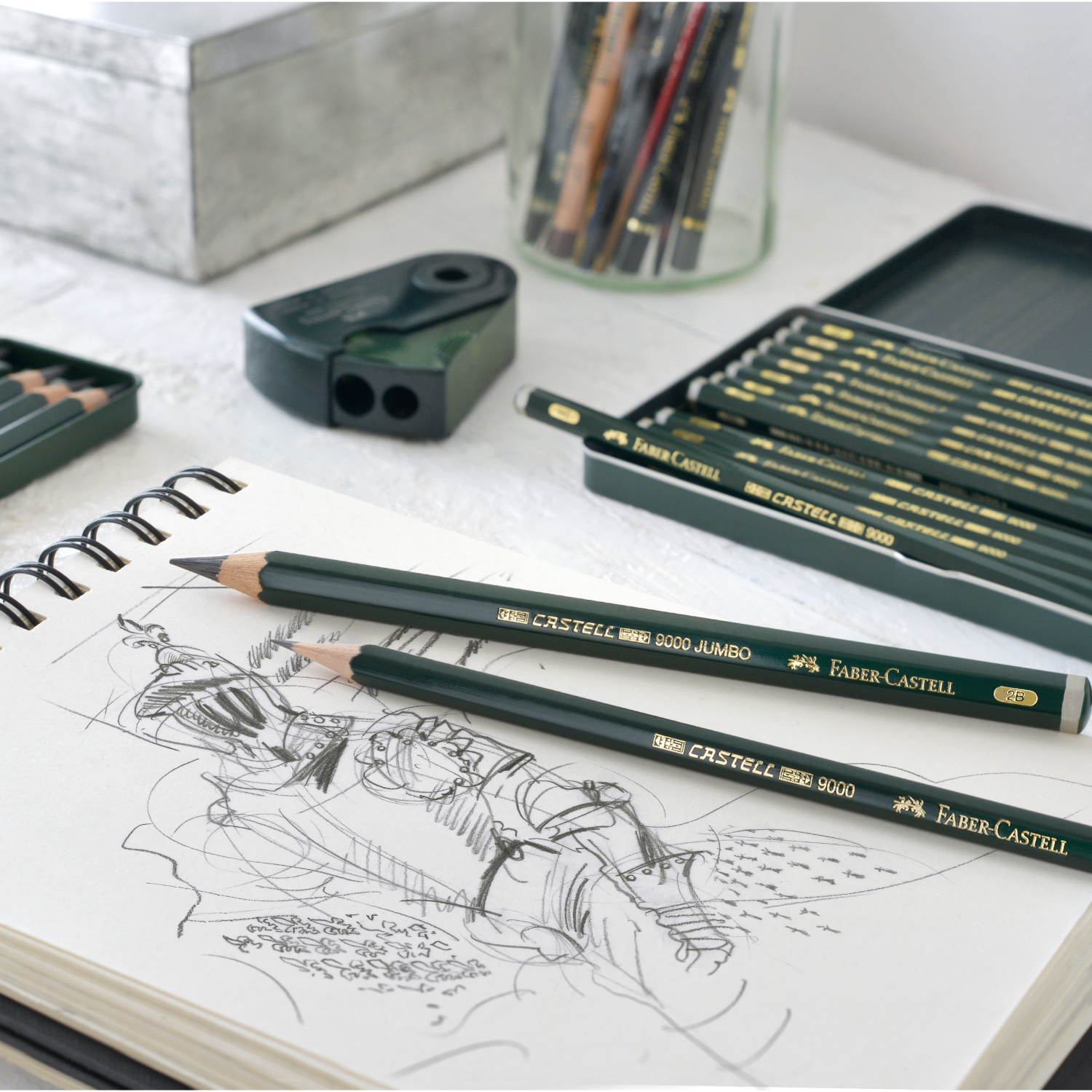 Castell 9000 Design Set Metalletui: Sechs Bleistifte und ein Spitzer auf einem Skizzenblock, ideal für Künstler.