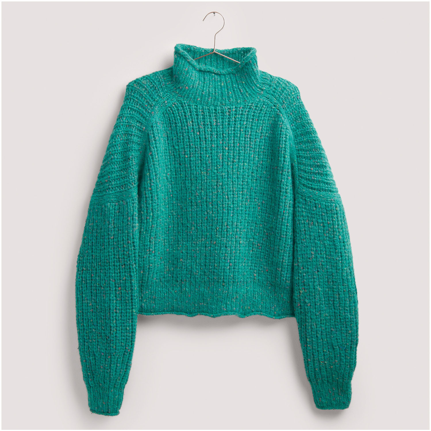 Strickset Pullover Modell 23: Türkisfarbener Pullover mit Rollkragen, aus grobem Strick, hängend an einem Kleiderbügel.