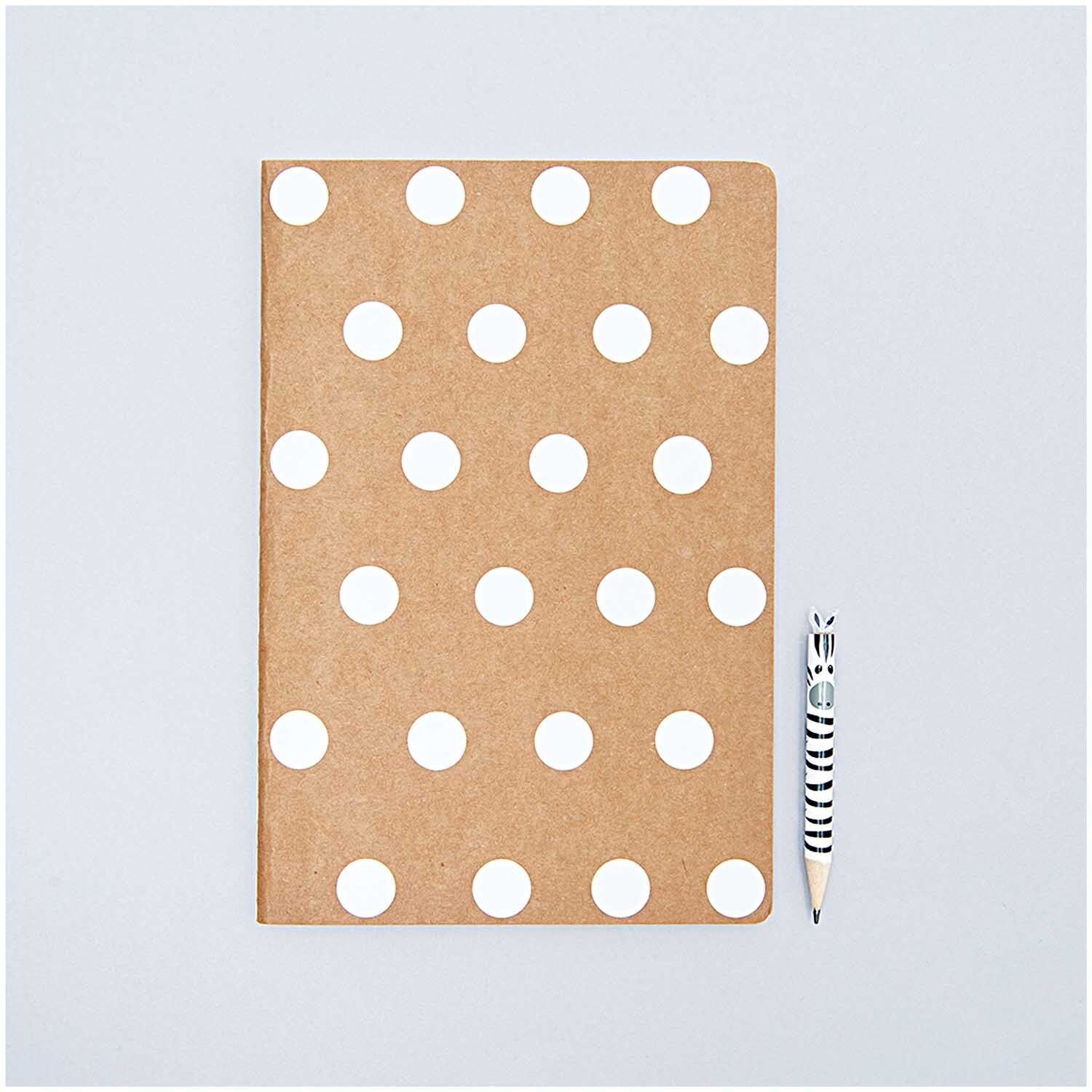 Office Sticker Punkte 15mm 4 Bogen: Braunes Notizbuch mit weißen Punkten, daneben ein gestreifter Bleistift. Ideal für kreative Designs.