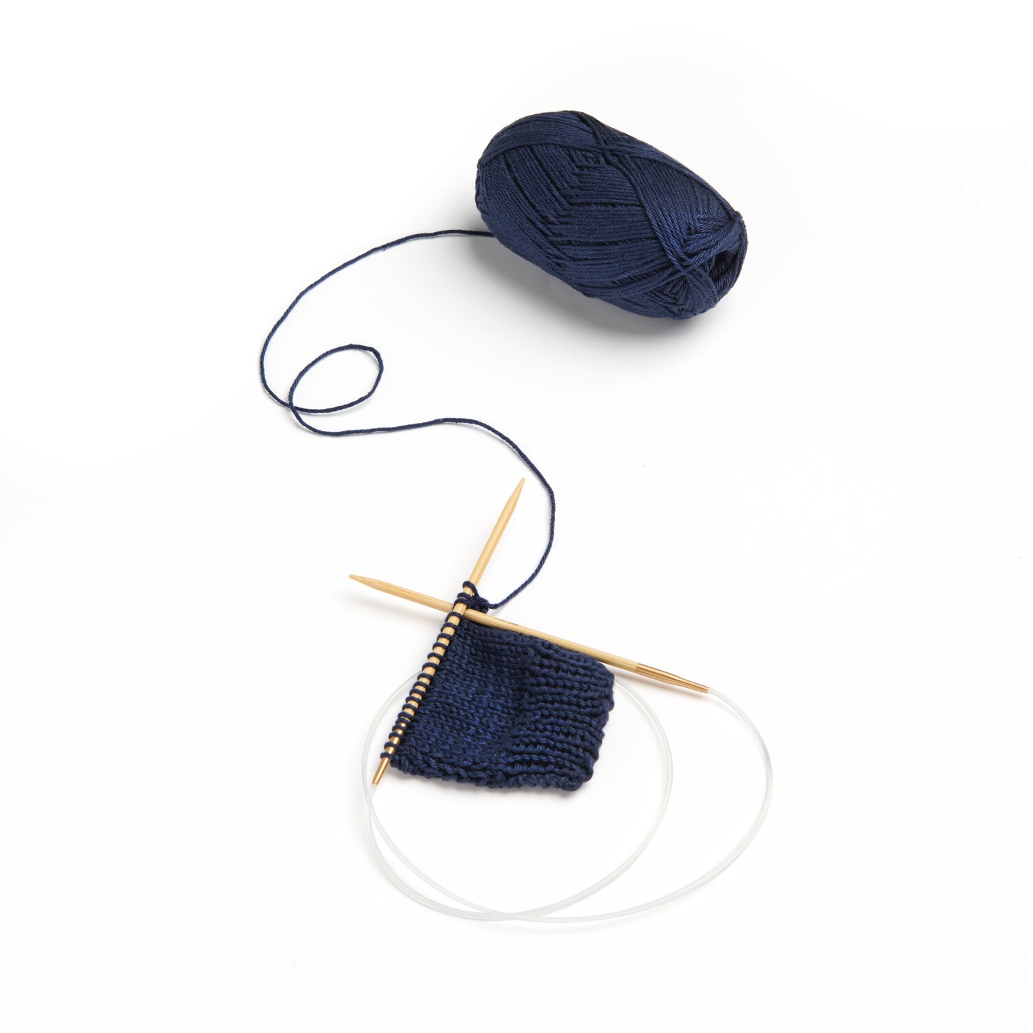 Rico Cotton: Dunkelblaues Garnknäuel mit Stricknadeln und begonnenem Strickstück, ideal für Frühling-Sommer-Projekte.