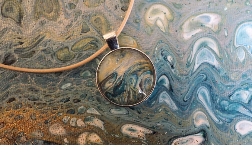 Anleitung DIY Pouring Schmuck: Rundes Anhänger-Design mit blau-grünen Wirbelmustern auf Lederband.