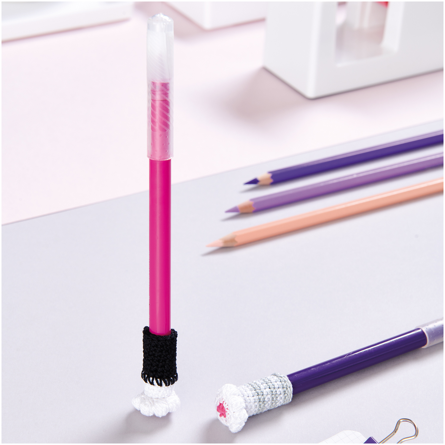 Essentials Crochet: Bunte Stifte mit gehäkelten Haltern auf einem Schreibtisch, ideal für kreative Projekte.