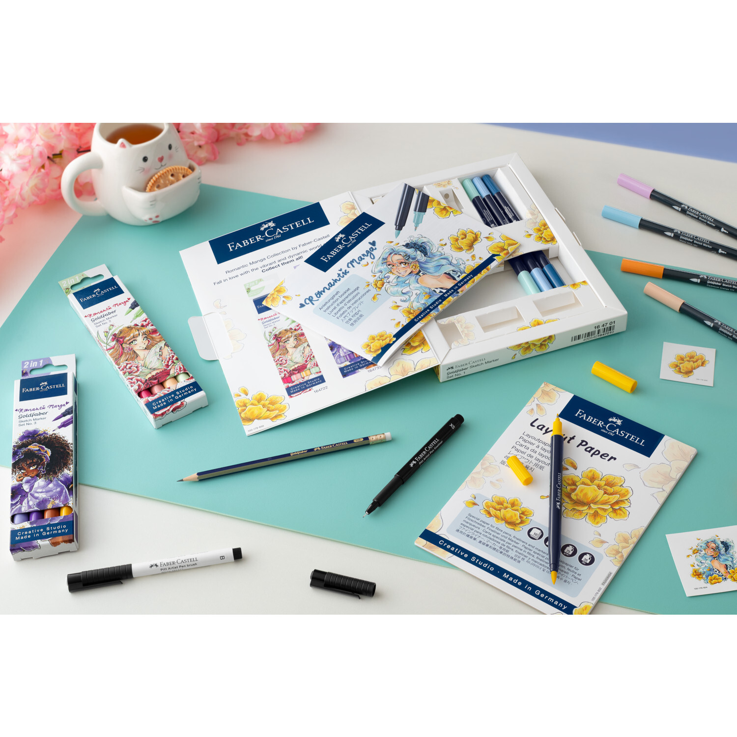 Goldfaber Sketch Marker Romantic Manga 2 Set auf blauem Tisch mit Faber Castell Stiften und Papier. Ideal für kreative Zeichnungen.