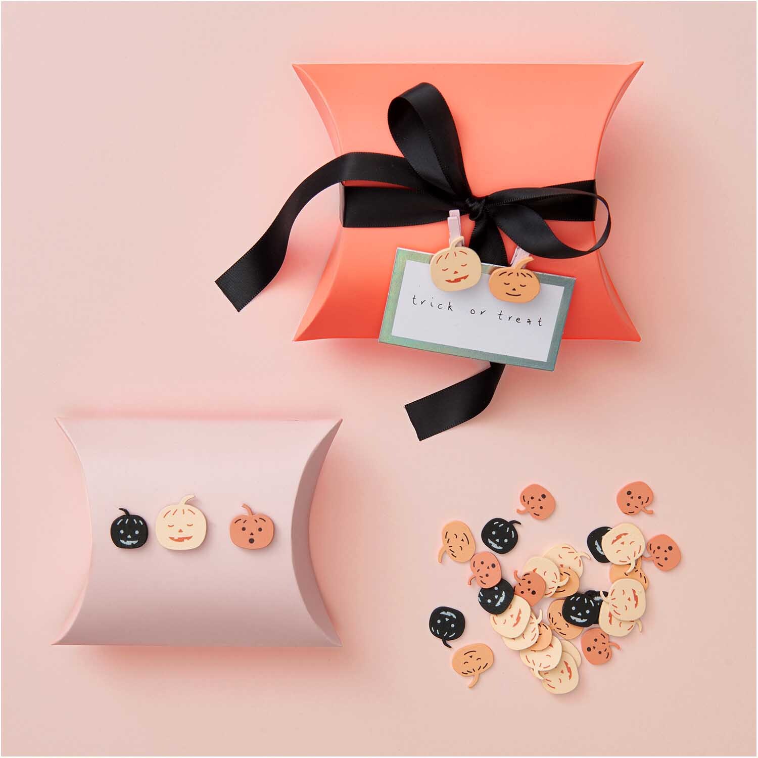 Holzclips Kürbis Mix: Mehrfarbige Kürbis-Holzclips von Rico Design, dekorativ auf Geschenkboxen arrangiert.