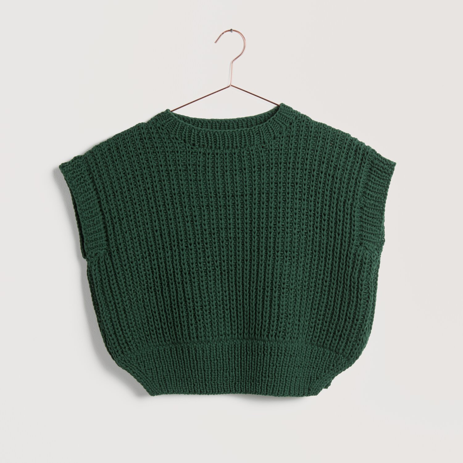 Strickset Pullunder Modell 23 aus Lovewool No. 22 in Efeu. Handgestrickter, ärmelloser Pullover auf einem Kleiderbügel.