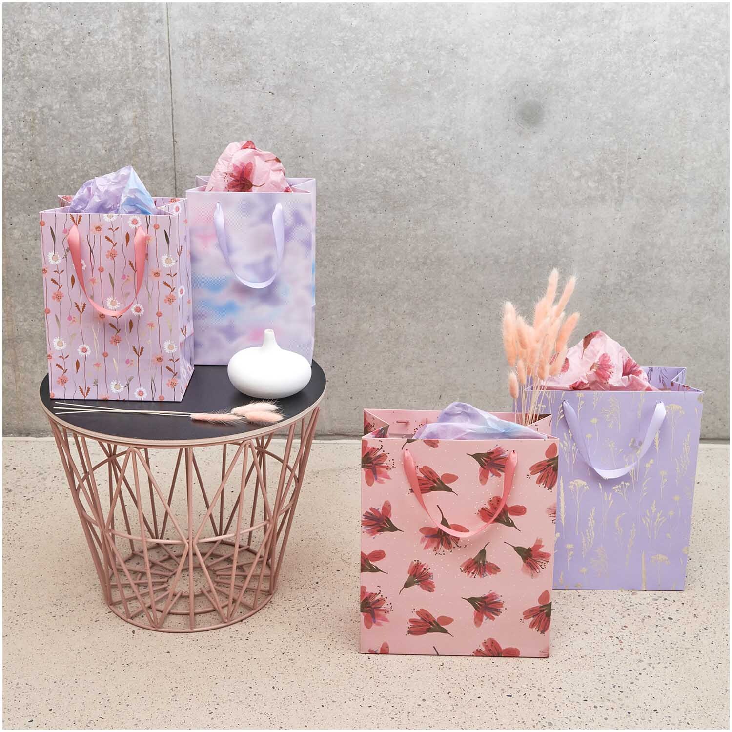 Paper Poetry Geschenktüte mit Gräsermotiv in Lila von Rico Design, neben anderen Tüten auf einem Tisch arrangiert.