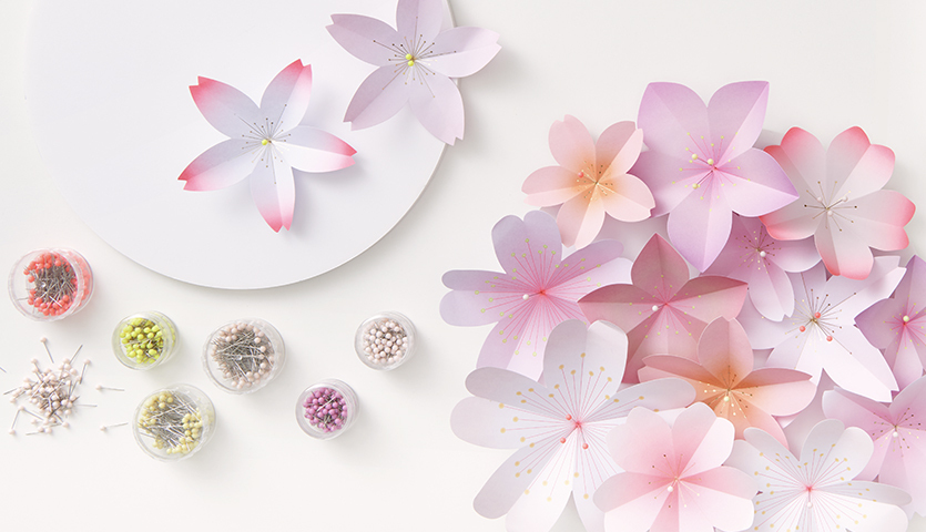 Bastelanleitung 3D-Papierblütenbild: Verschiedene rosa und weiße Papierblüten mit Bastelmaterialien.