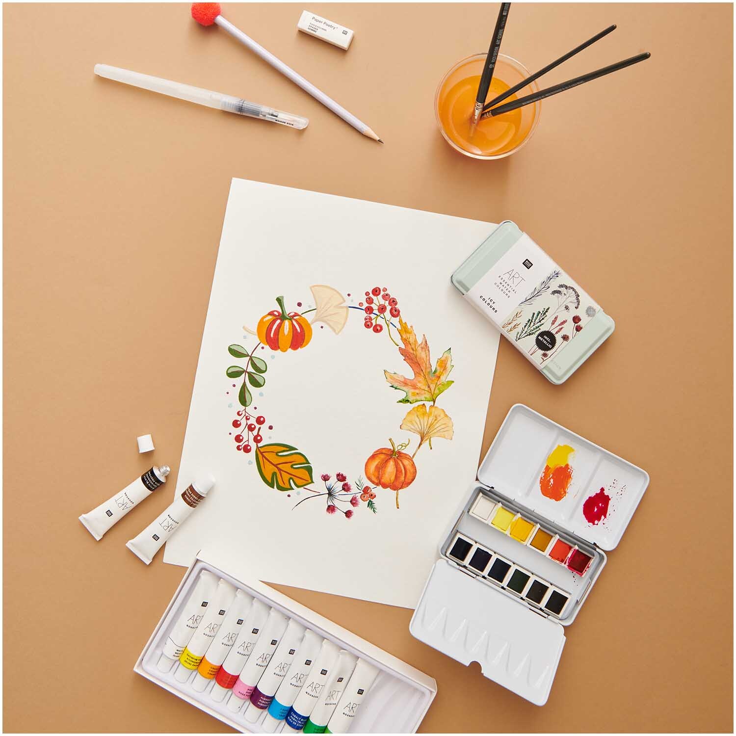 ART Künstler Acrylfarben-Set Basic 12x12ml zeigt eine herbstliche Malerei mit Blättern und Kürbissen, umgeben von Malutensilien.