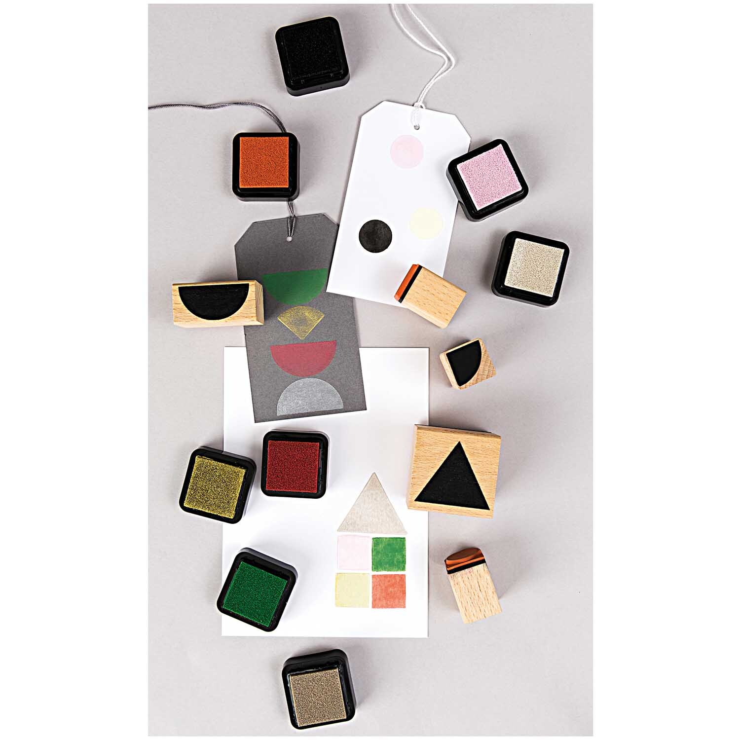 Paper Poetry Stempelset geometrische Symbole rund, 6-teilig, von Rico Design, mit bunten Stempelkissen und Holzstempeln auf einem Tisch arrangiert.