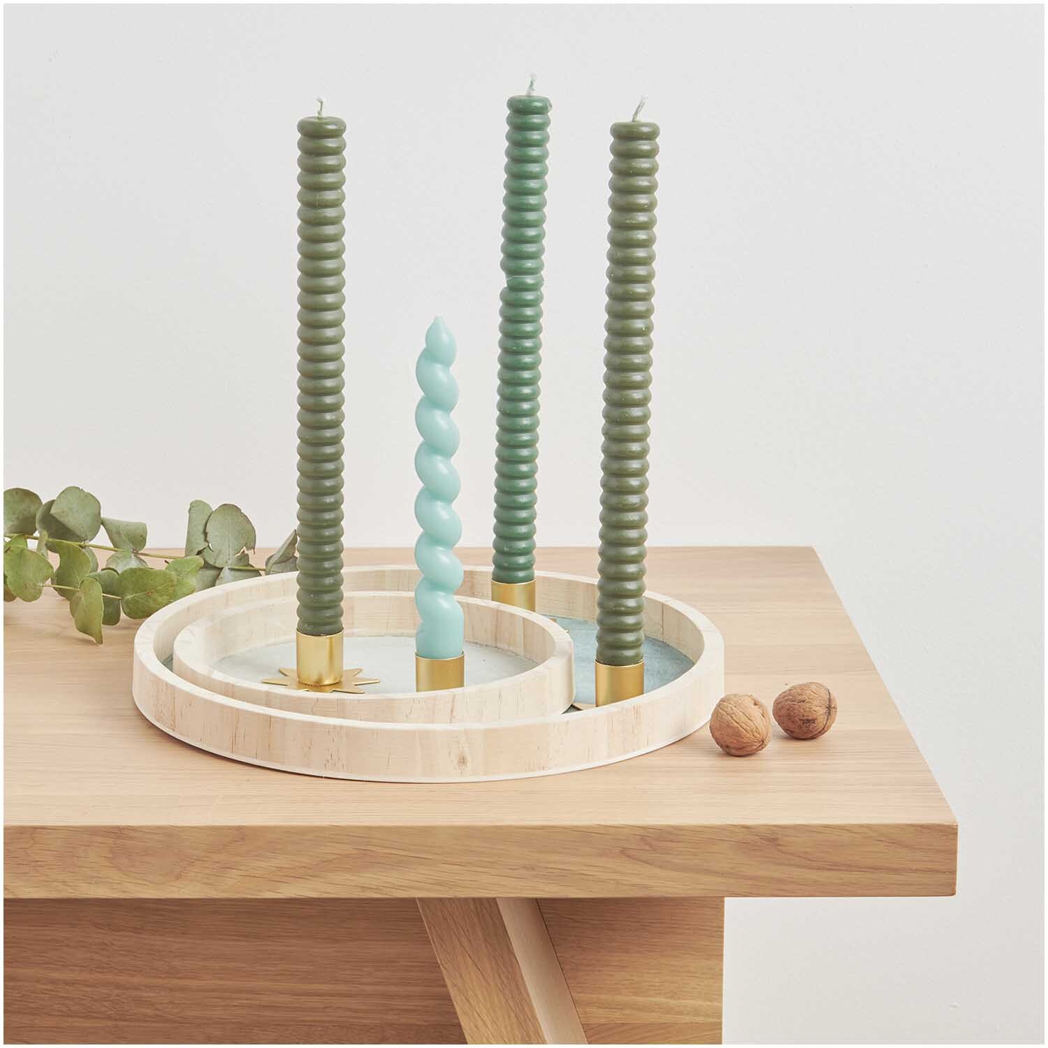 Holztablett natur mit grünen und blauen Kerzen von Rico Design auf einem Holztisch, dekoriert mit Eukalyptusblättern und Walnüssen.