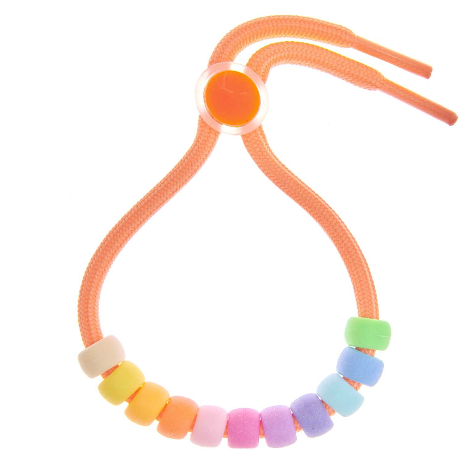 Itoshii - Ponii Beads in mattem Regenbogen-Design auf einem orangefarbenen Band von Rico Design.