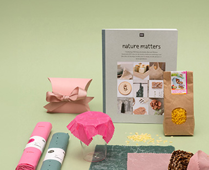 Verschiedene Stoffabschnitte, ein DIY-Buch, verpackte Bienenwachs Pastillen und Bienenwachstücher. Fotosetting grüne Wand.