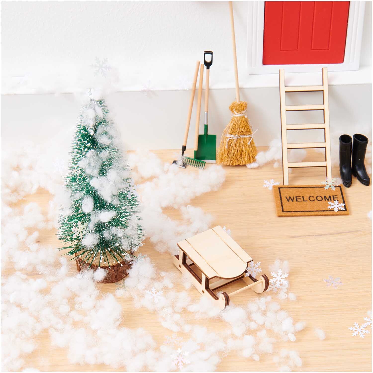 Wichtelwelt Deko Set Schnee mit Miniatur-Weihnachtsbaum, Schlitten und Besen auf Holzuntergrund.