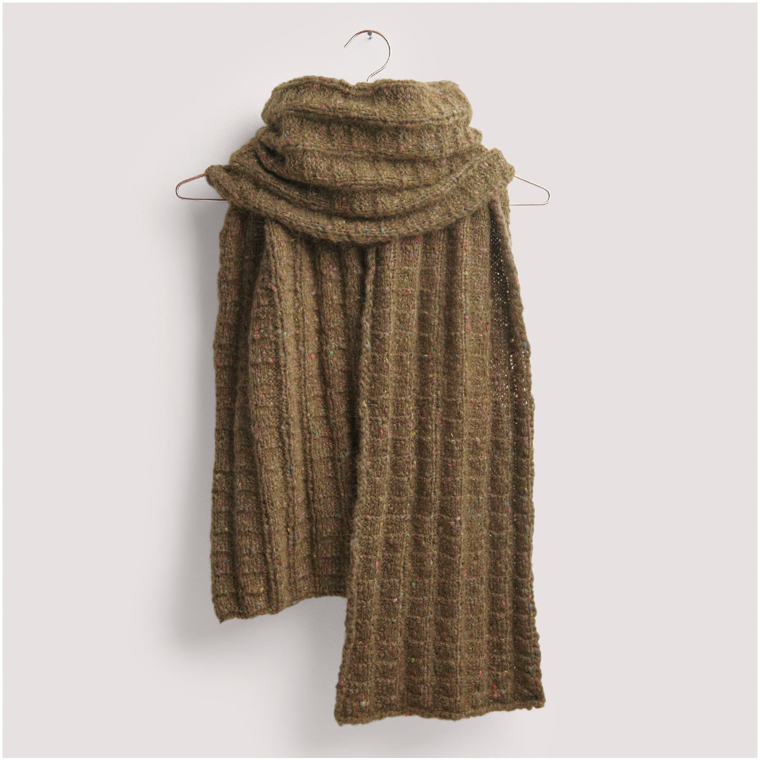 Strickset Schal Modell 05 aus Die Neue Masche Nr. 8, brauner Schal mit grobem Strickmuster, hängend an einem Kleiderbügel vor hellem Hintergrund.