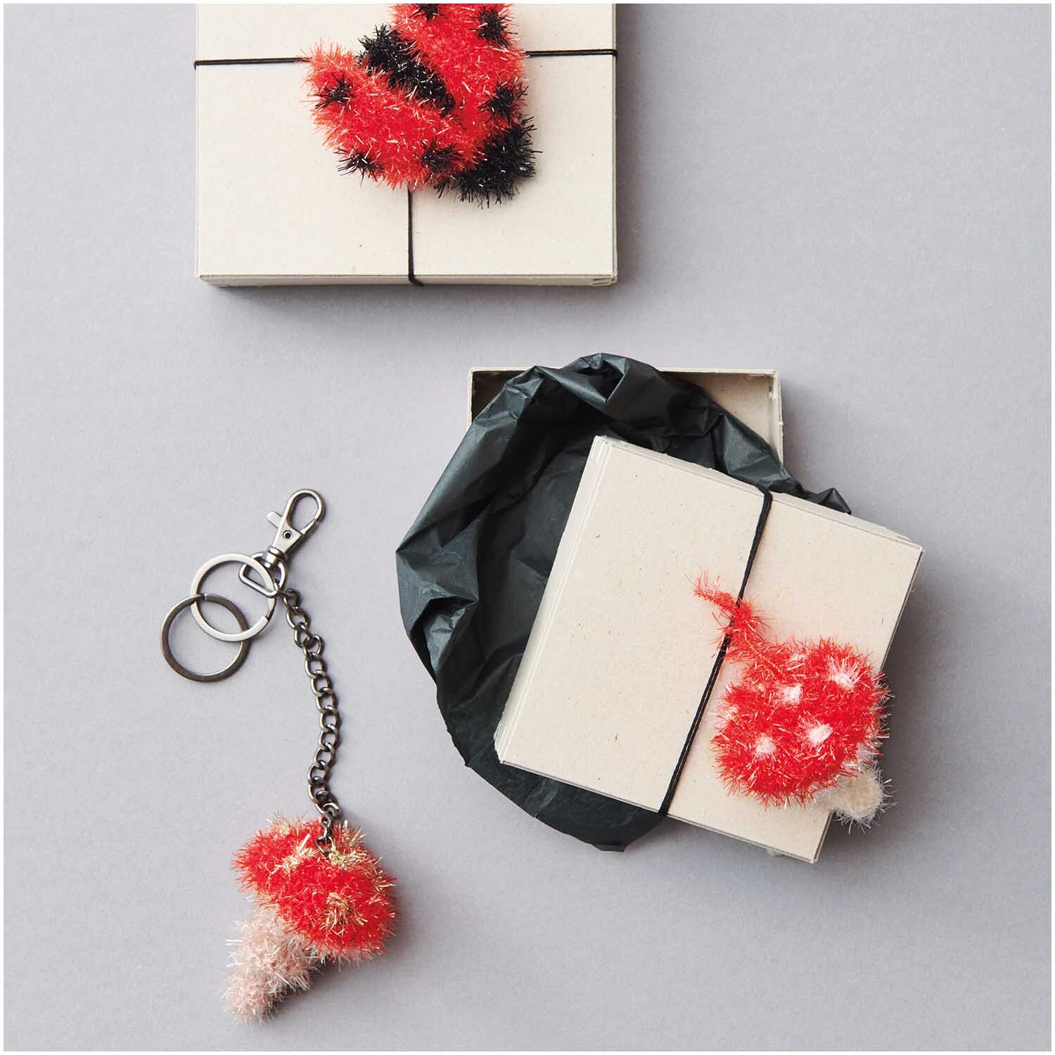 Creative Bubble Set Good Luck! von Rico Design mit roten und schwarzen Strickaccessoires, Geschenkbox und Schlüsselanhänger.