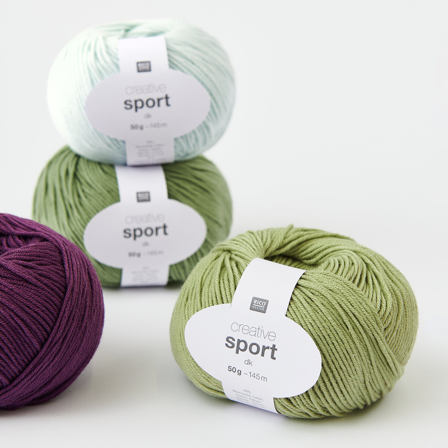 Creative Sport dk Sortiment VIII 80-teilig: Drei Wollknäuel in Eisblau, Moos und Bordeaux von Rico Design auf weißem Hintergrund.