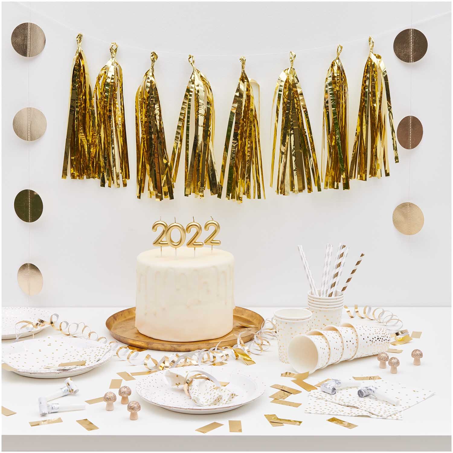 Paper Poetry Girlande Quasten gold 2,8m von Rico Design dekoriert eine festliche Tafel mit goldenen Akzenten und einer Torte mit der Zahl 2022.