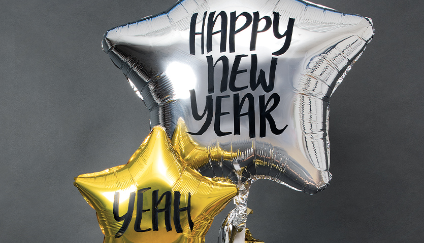 Anleitung Folienballon als Silvesterdeko: Zwei sternförmige Ballons in Silber und Gold mit Neujahrsgrüßen.