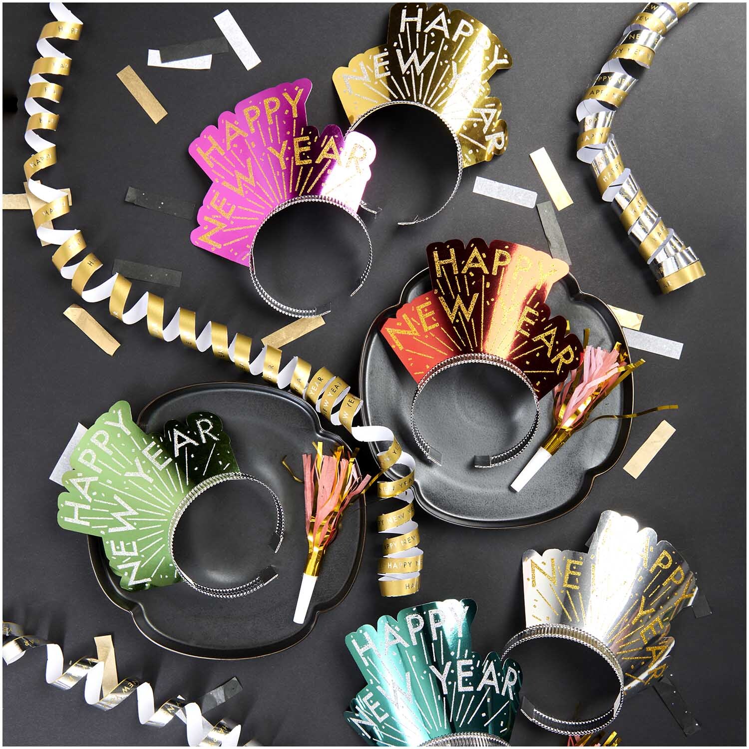 Haarreifen Happy New Year 6 Stück von Rico Design auf schwarzem Hintergrund mit bunten Partydekorationen.