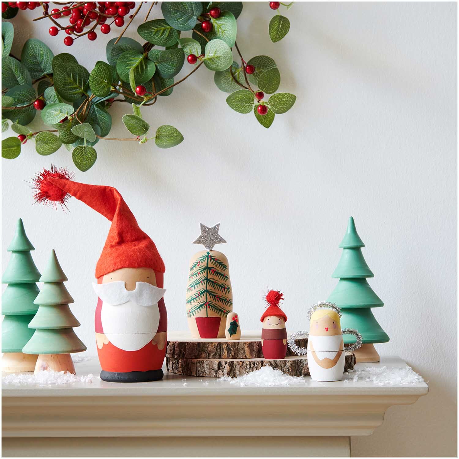 Matroschka Puppenrohlinge 5 Stück von Rico Design auf einem Kaminsims mit Weihnachtsdekoration, darunter Tannenbäume und ein Weihnachtsmann.