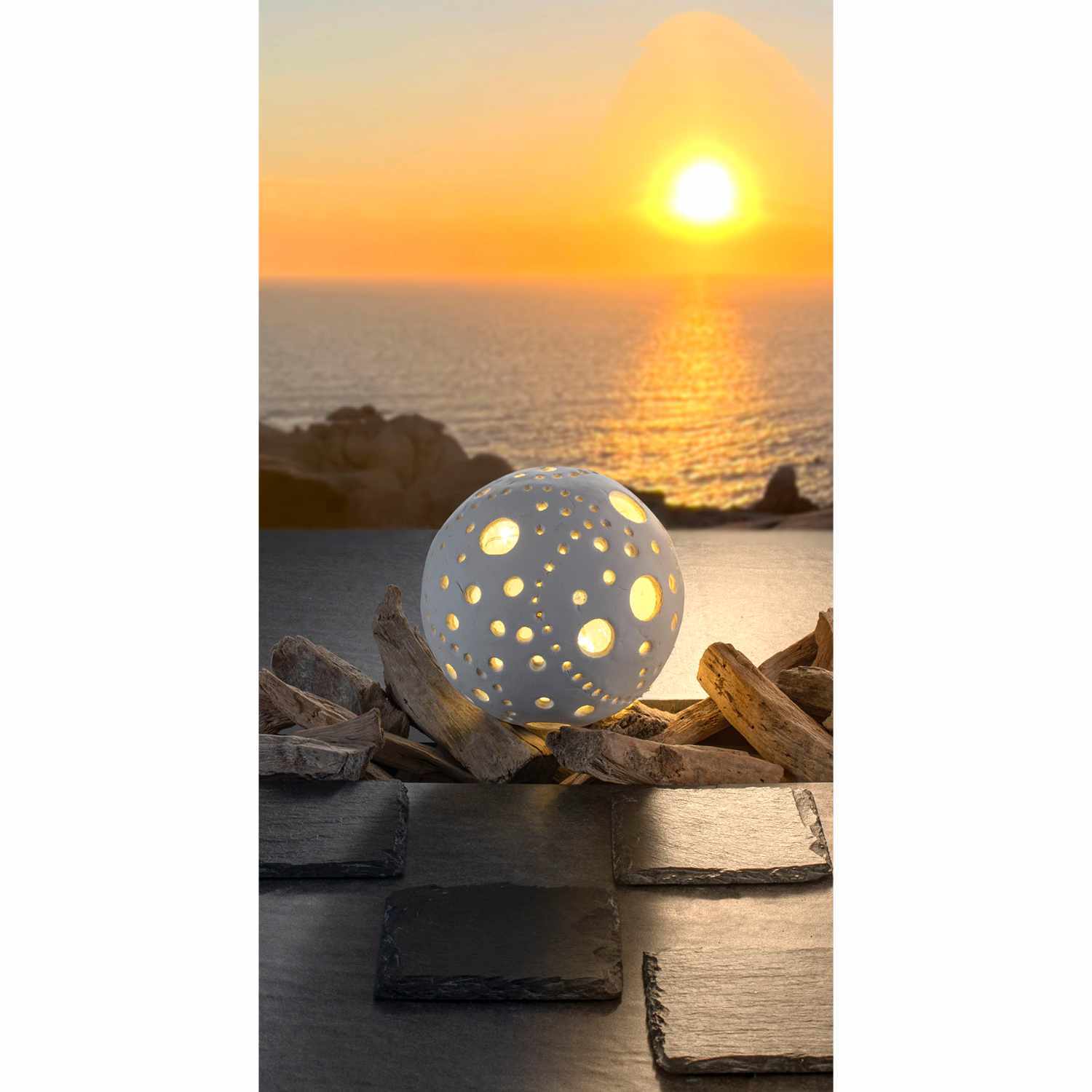Keramin-S 1000g von Glorex: Eine leuchtende Kugel mit Lochmuster vor einem Sonnenuntergang am Meer.