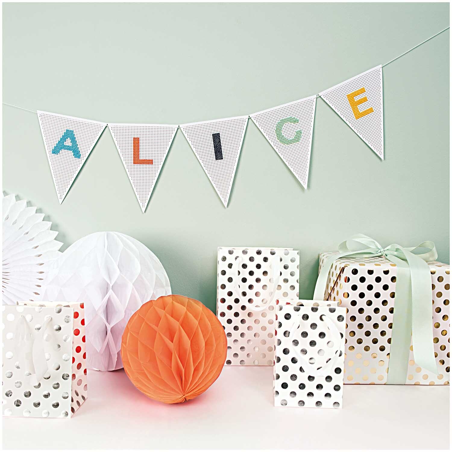 Paper Poetry Geschenktüte mit silbernen Punkten, umgeben von dekorativen Papierbällen und Geschenken. Ideal für stilvolle Präsentationen.