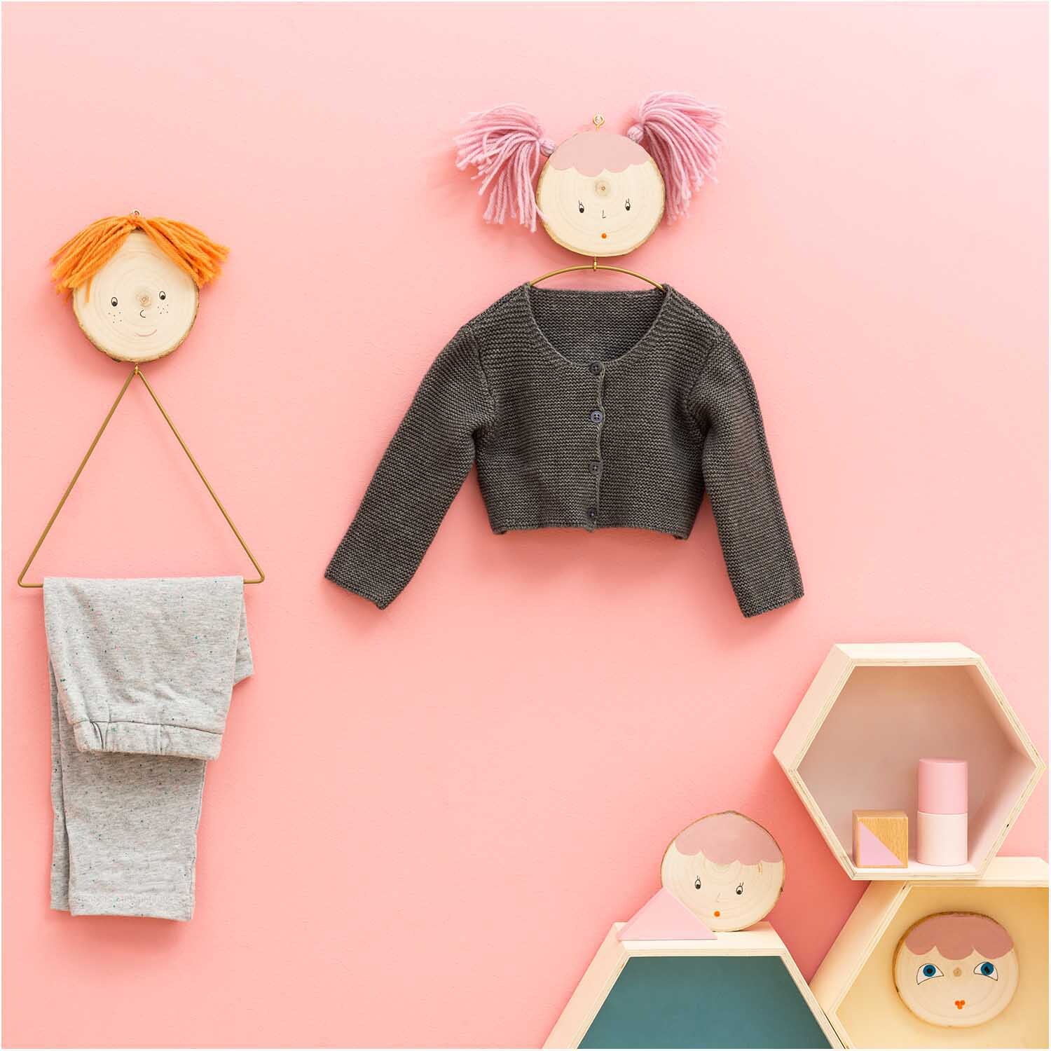 Metallring Dreieck gold: Kinderzimmer-Deko mit grauem Cardigan und grauer Hose an rosa Wand.