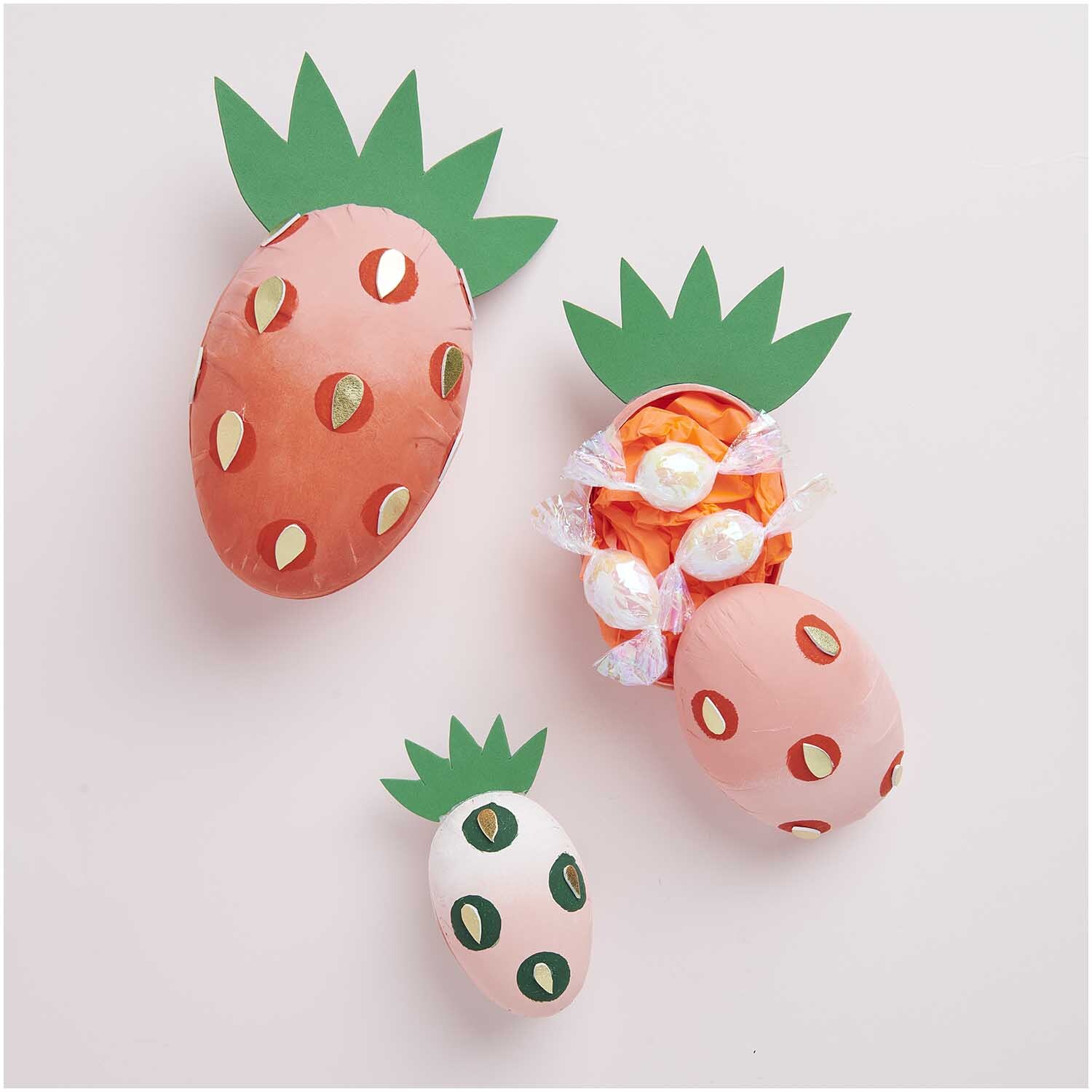 Pappmaché Eier in Form von Erdbeeren mit grünen Blättern, ideal für kreative Dekorationen.