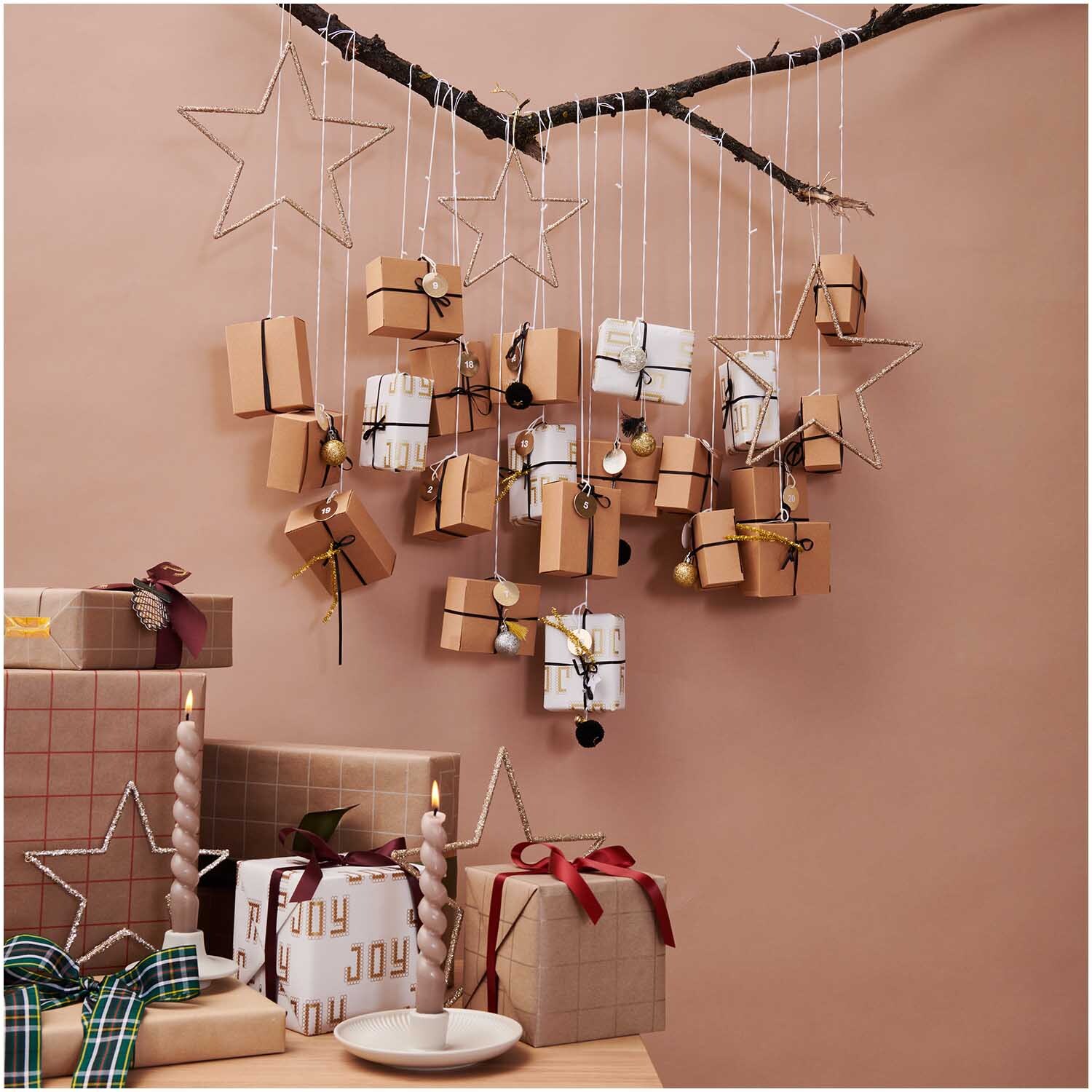Paper Poetry Adventskalender Boxen Set 24teilig: Hängende Boxen an einem Ast, dekoriert mit Sternen und Kerzen, in natürlichen Farben.