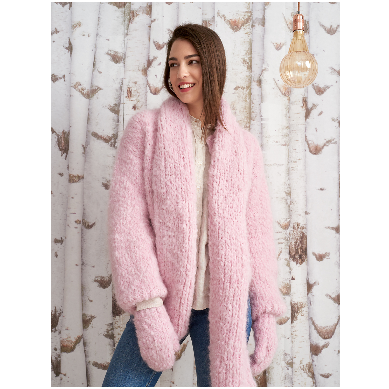 Fashion Fine Fur Super Chunky: Frau in rosa Strickjacke vor Birkenwaldtapete, lächelnd.