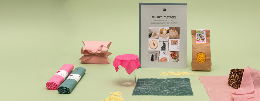 Verschiedene Stoffabschnitte, ein DIY-Buch, verpackte Bienenwachs Pastillen und Bienenwachstücher. Fotosetting grüne Wand.