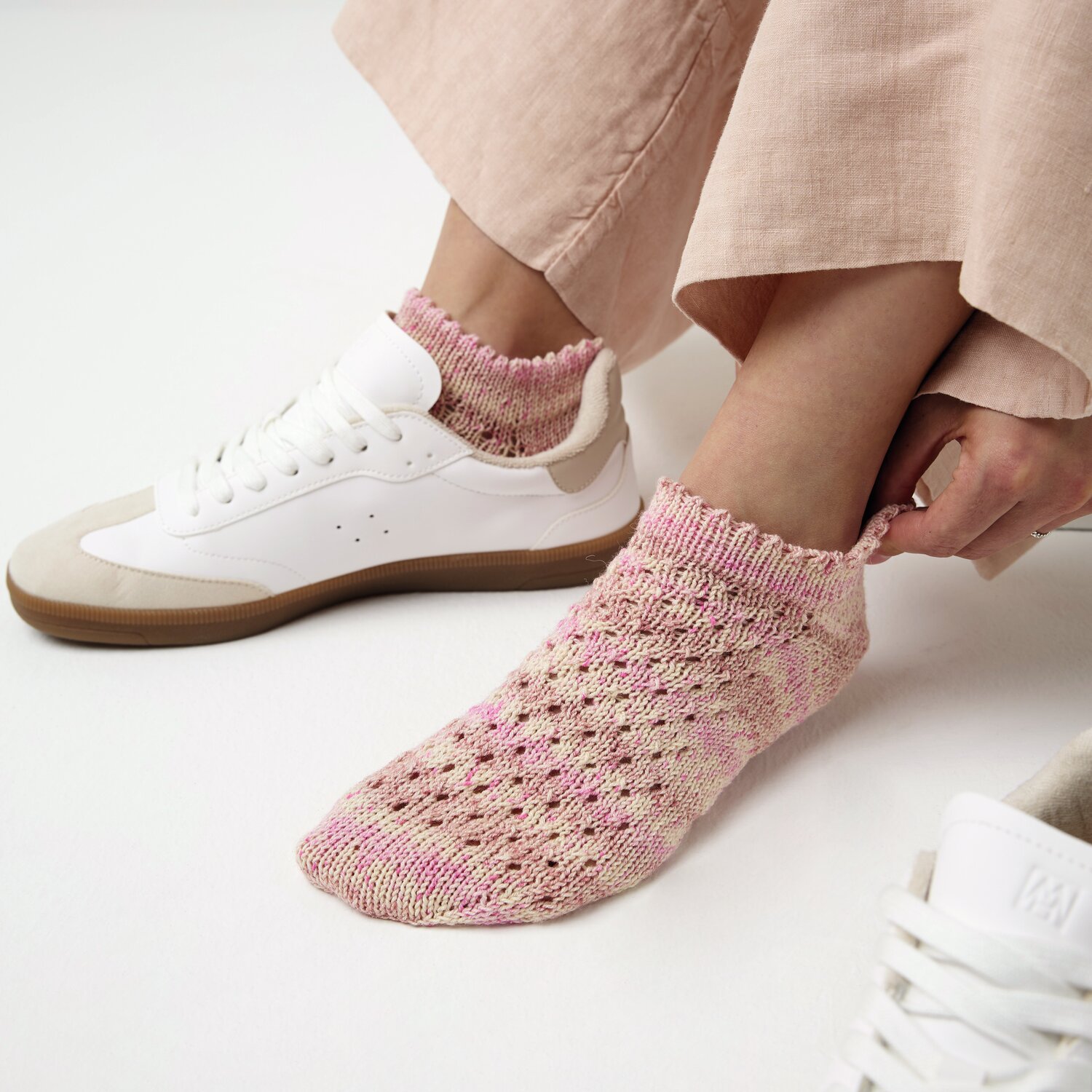 Strickset Socken Modell 14a: Rosa gestrickte Socken mit Lochmuster, getragen mit weißen Sneakern.