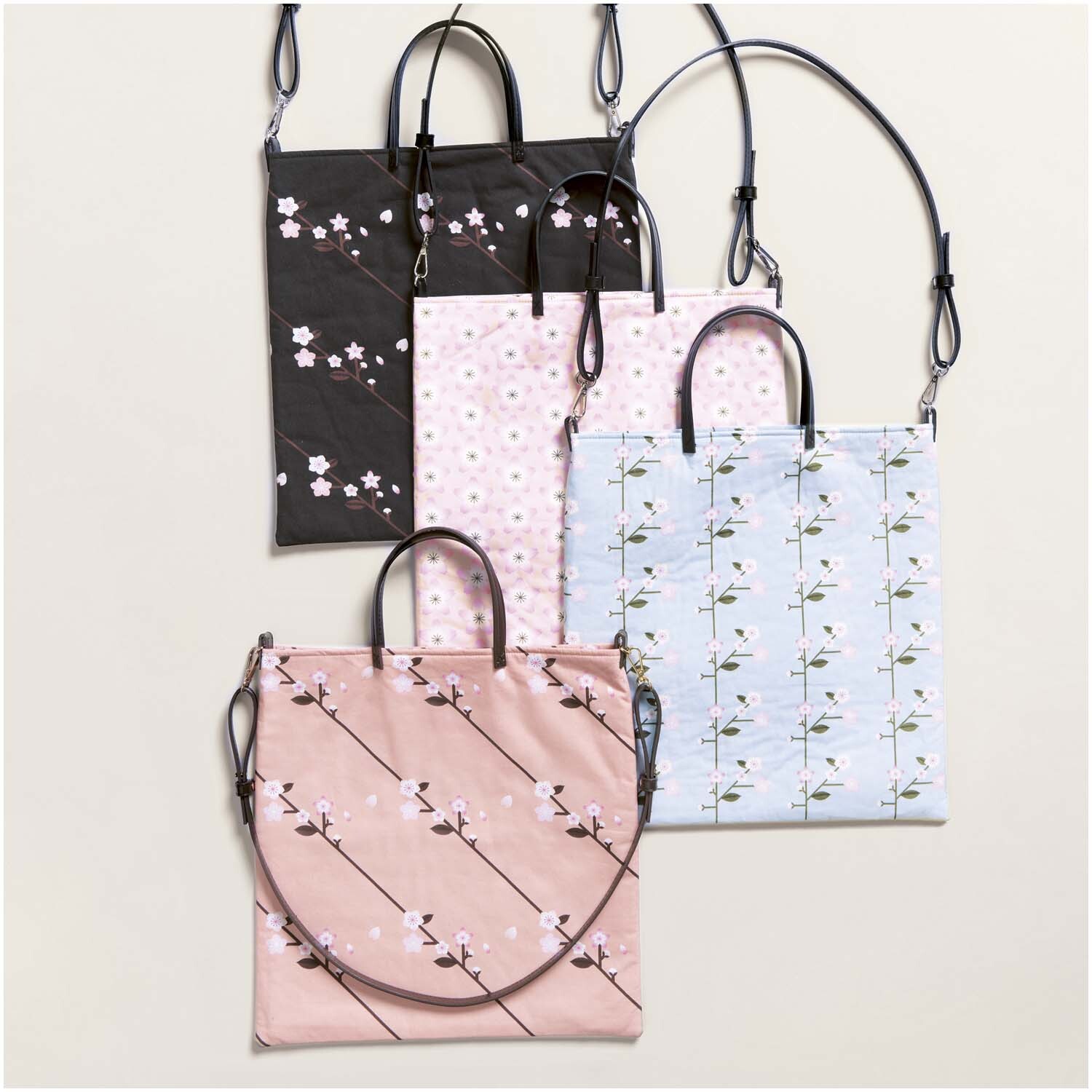 Meterware Baumwoll-Popelin schwarz Sakura Zweige: Vier Taschen mit floralen Mustern in verschiedenen Farben, ideal für stilvolle Accessoires.