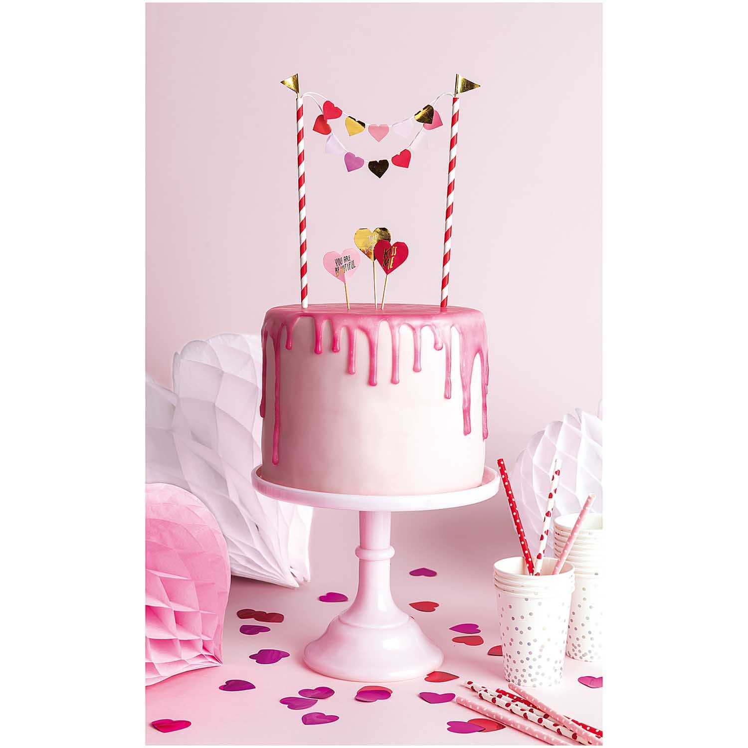 Kuchendekoration Herzen von Rico Design: Rosa-weiße Torte mit Herzdeko und Papierstrohhalmen.