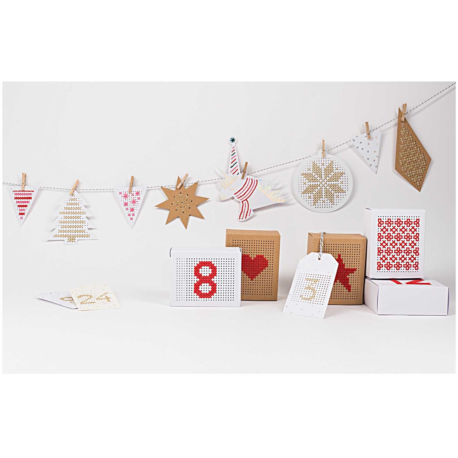 Paper Poetry Stickkarton Einhorn mit Garn und Nadel, dekorative Weihnachtsmotive und Geschenkschachteln auf einer Leine aufgehängt.