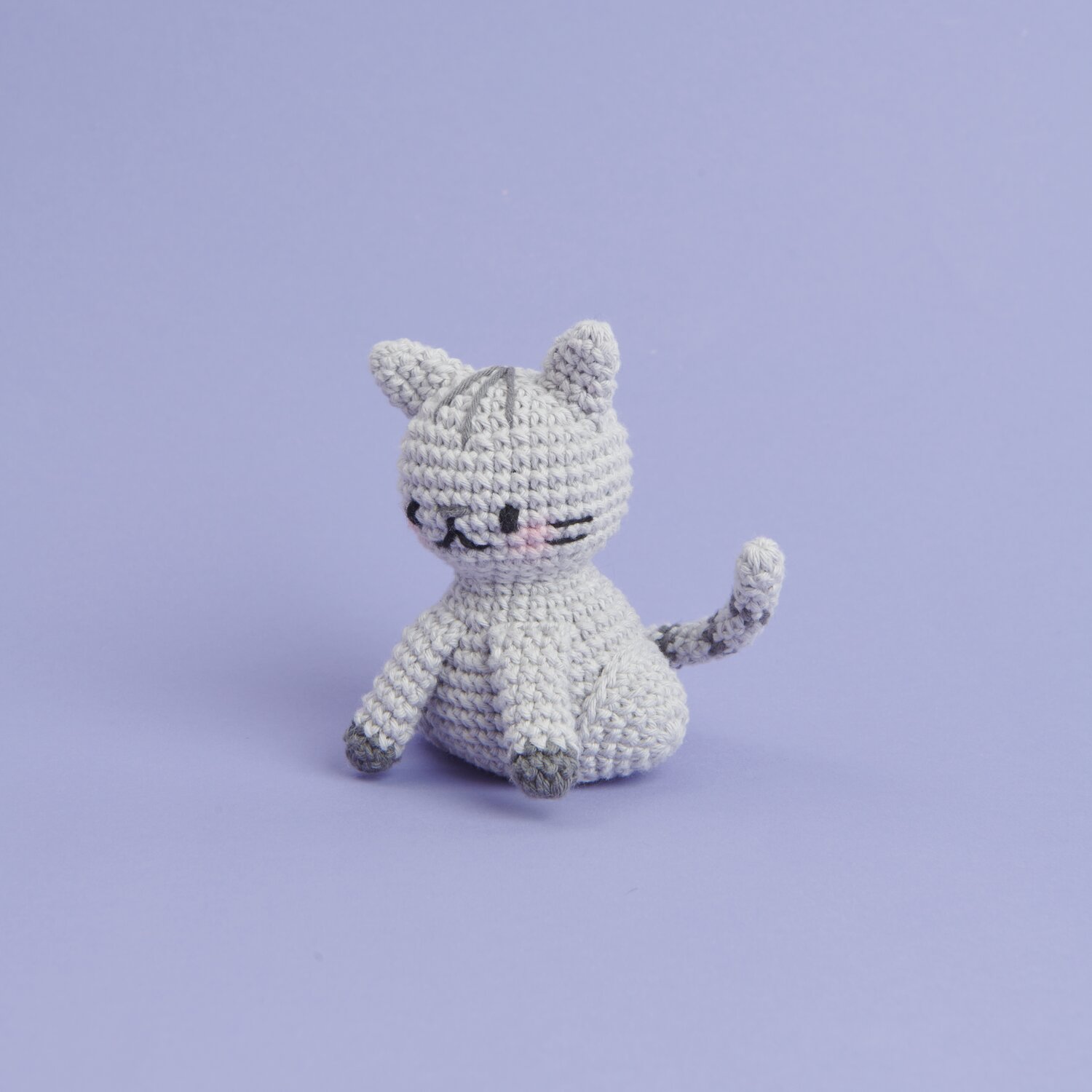 Ricorumi Mini Easy Häkelset - Katze: Graue, gehäkelte Katze von Rico Design auf lila Hintergrund.