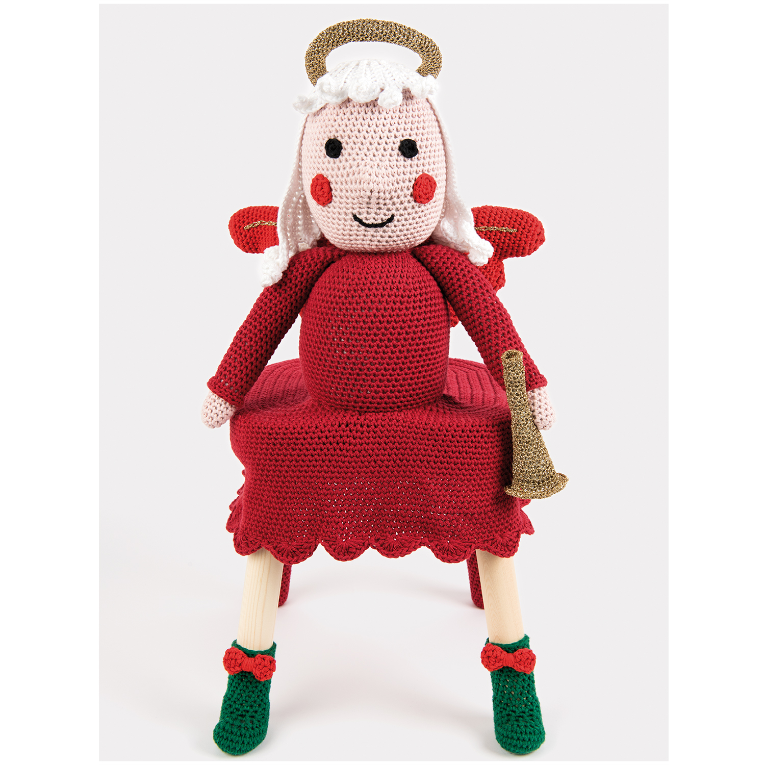 Creative Lamé: Gehäkelte Puppe in rotem Kleid mit goldenen Details und grünen Schuhen, hält eine Trompete.