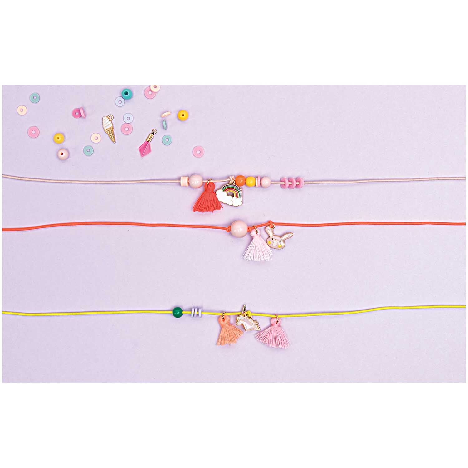 Anhänger Feder Mix candy 5 Stück: Bunte Armbänder mit Perlen und Anhängern auf pastellfarbenem Hintergrund.