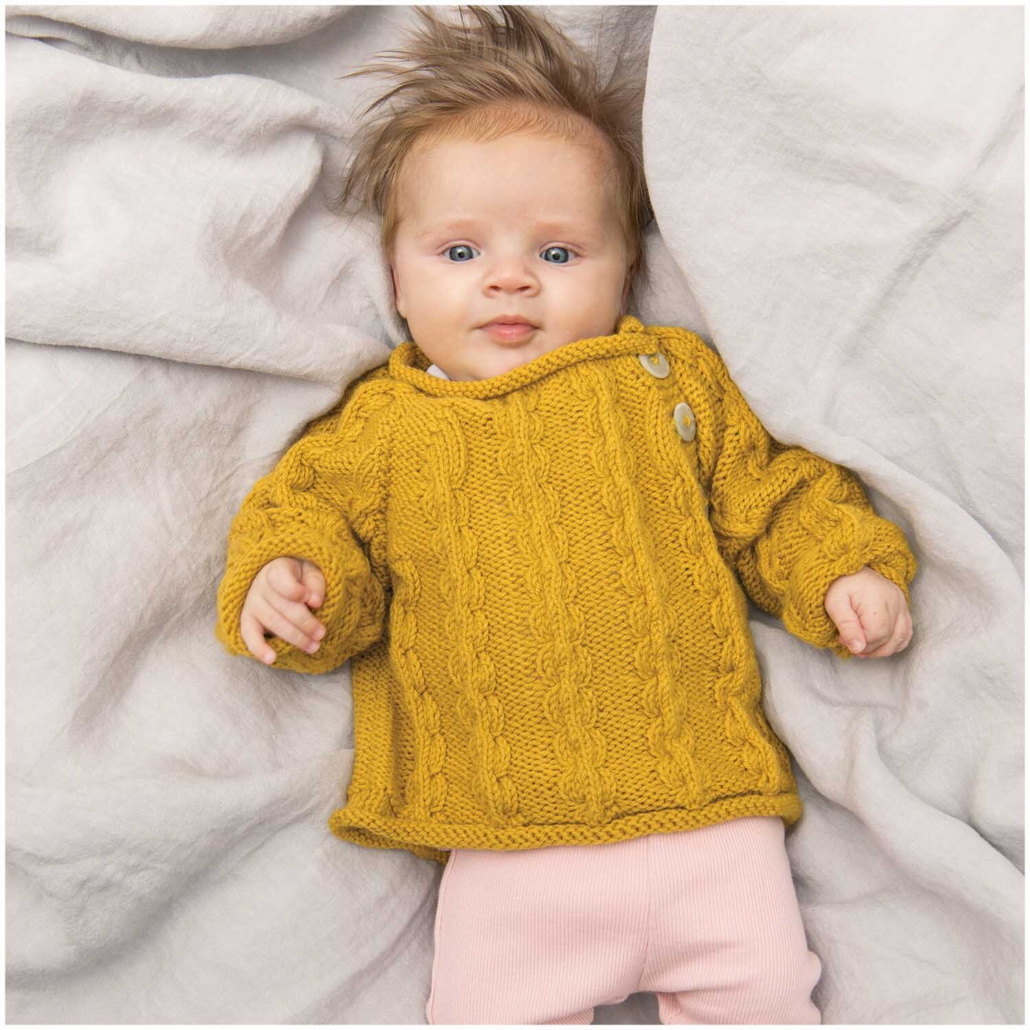 Rico Baby Classic dk: Ein Baby trägt einen gestrickten Pullover in Senf auf einer weichen Decke.