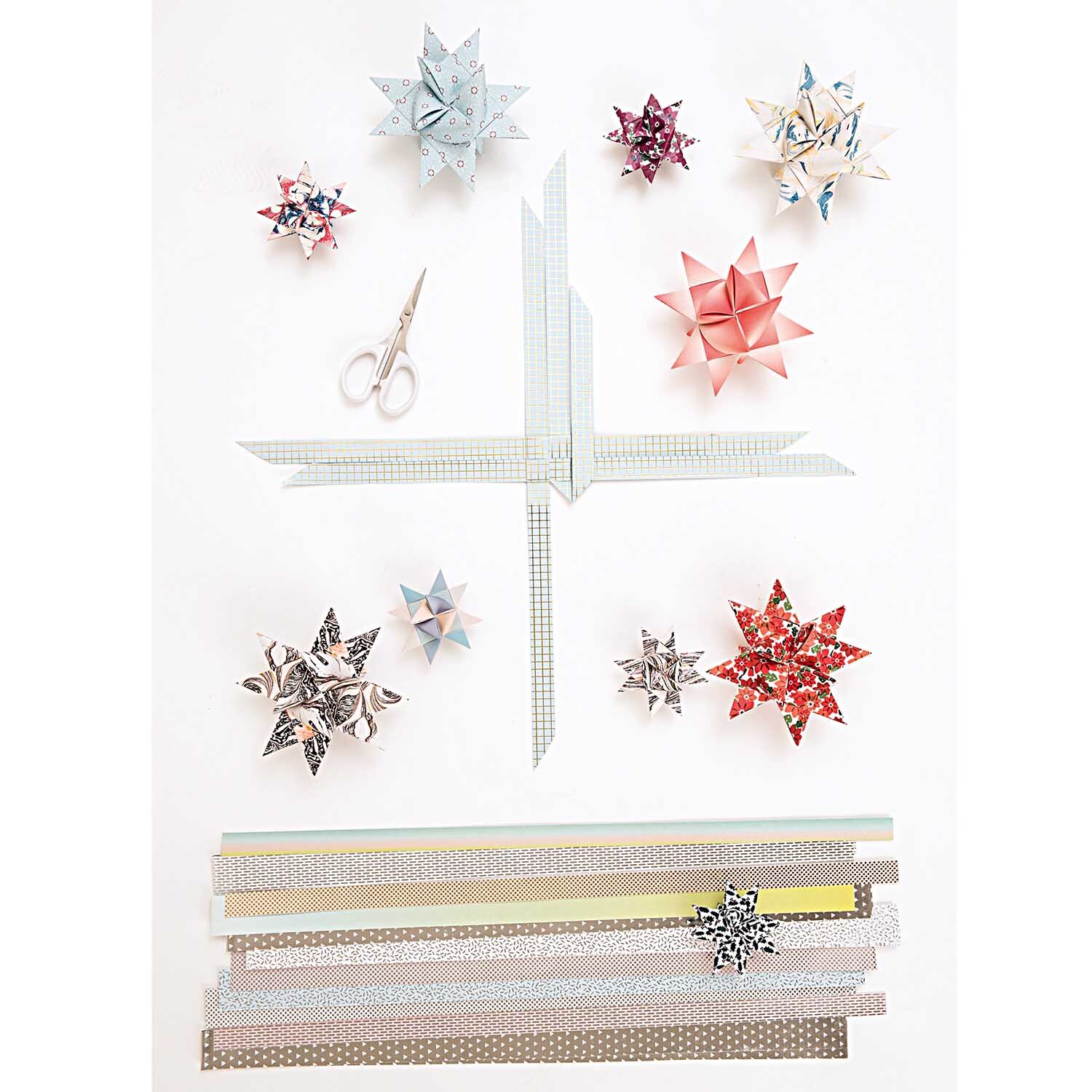 Präzisionsschere klein 10cm von Rico Design neben bunten Origami-Sternen und Papierstreifen.