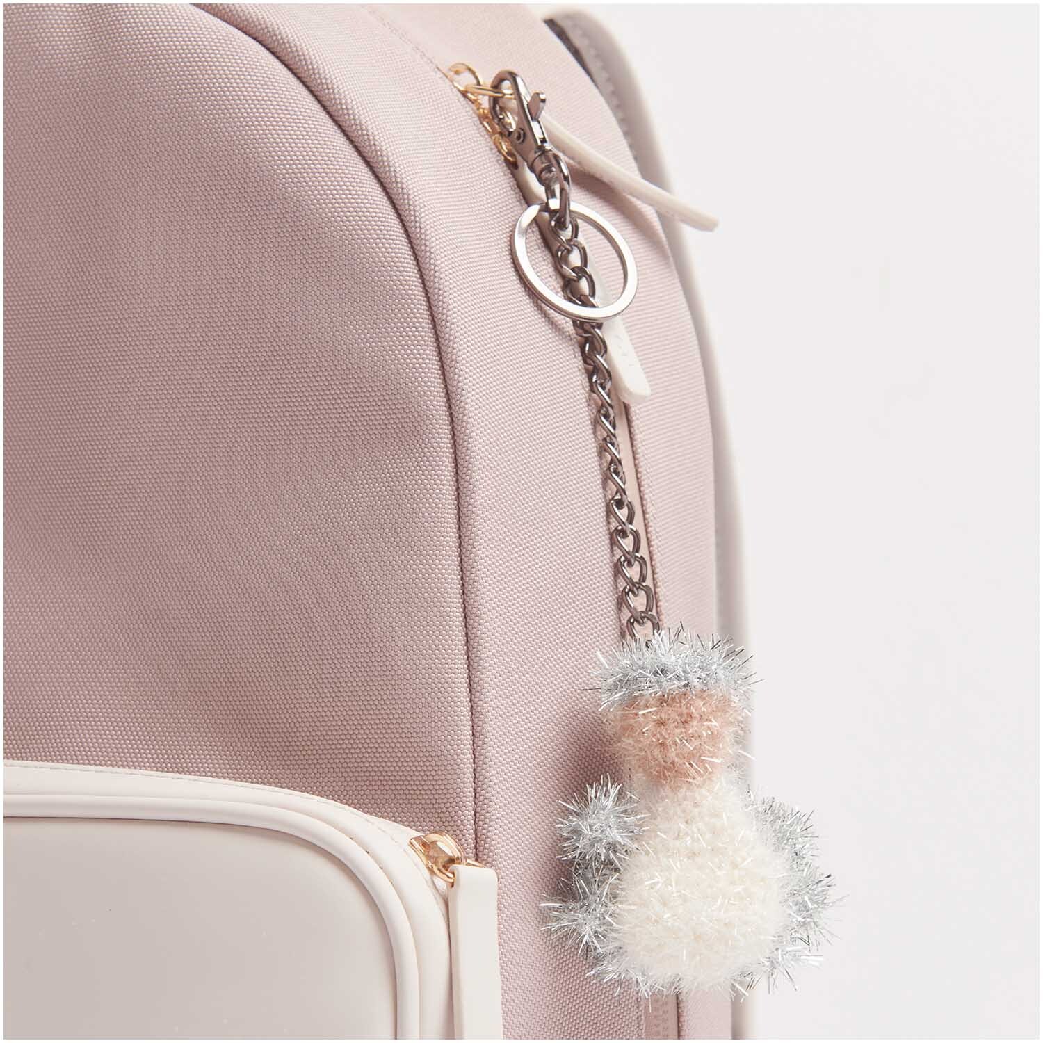 Creative Bubble Schlüsselanhänger aus Rico Design Garn in Metallic Silber an einem rosa Rucksack befestigt.