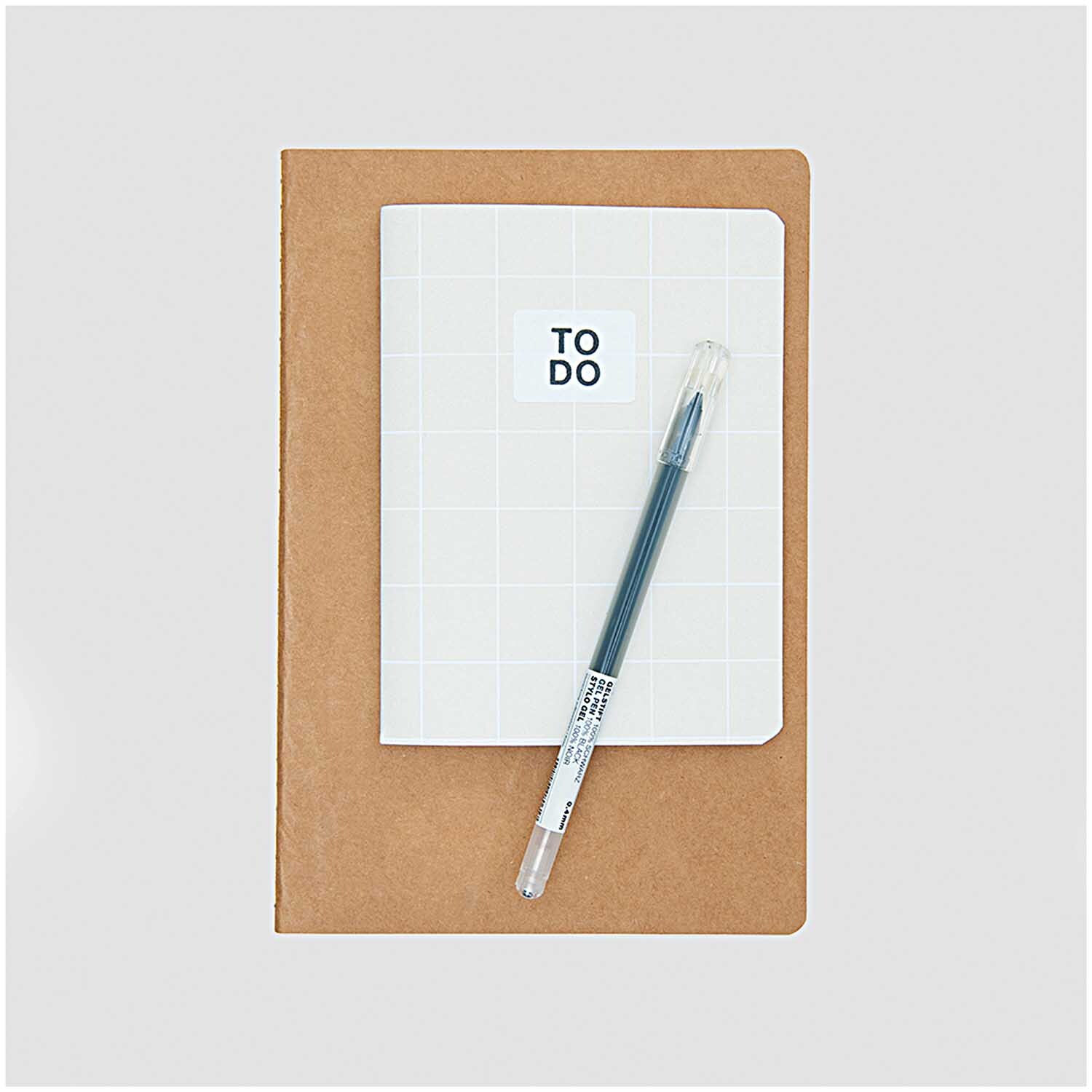 Paper Poetry Notizbuch A5 aus Kraftpapier mit unliniertem Design, daneben ein weißes Notizbuch und ein Stift. Ideal für kreative Notizen.