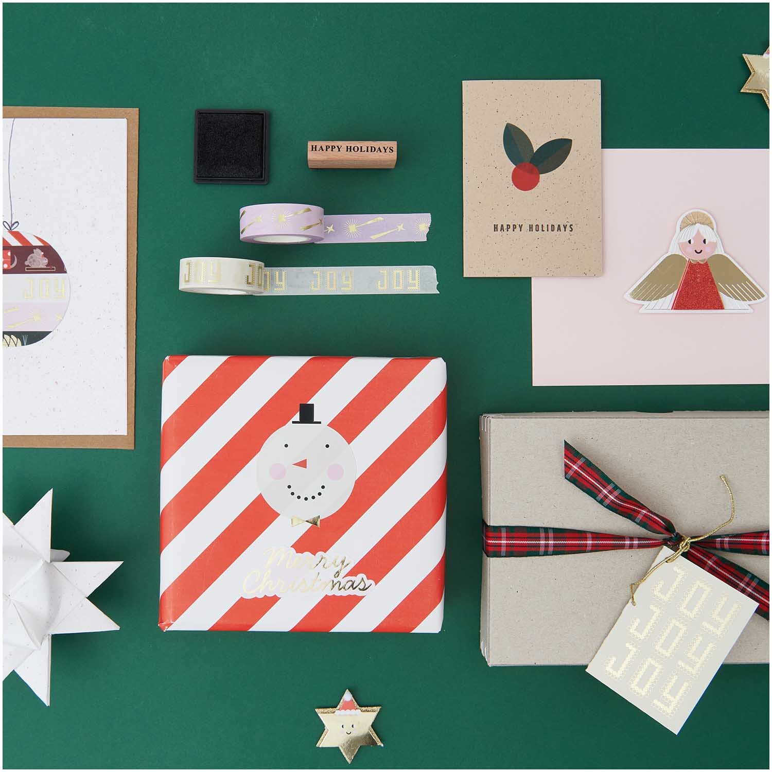 Paper Poetry XL Stempelset Merry Christmas, 27-teilig, auf grünem Hintergrund mit Geschenkpapier und Karten.